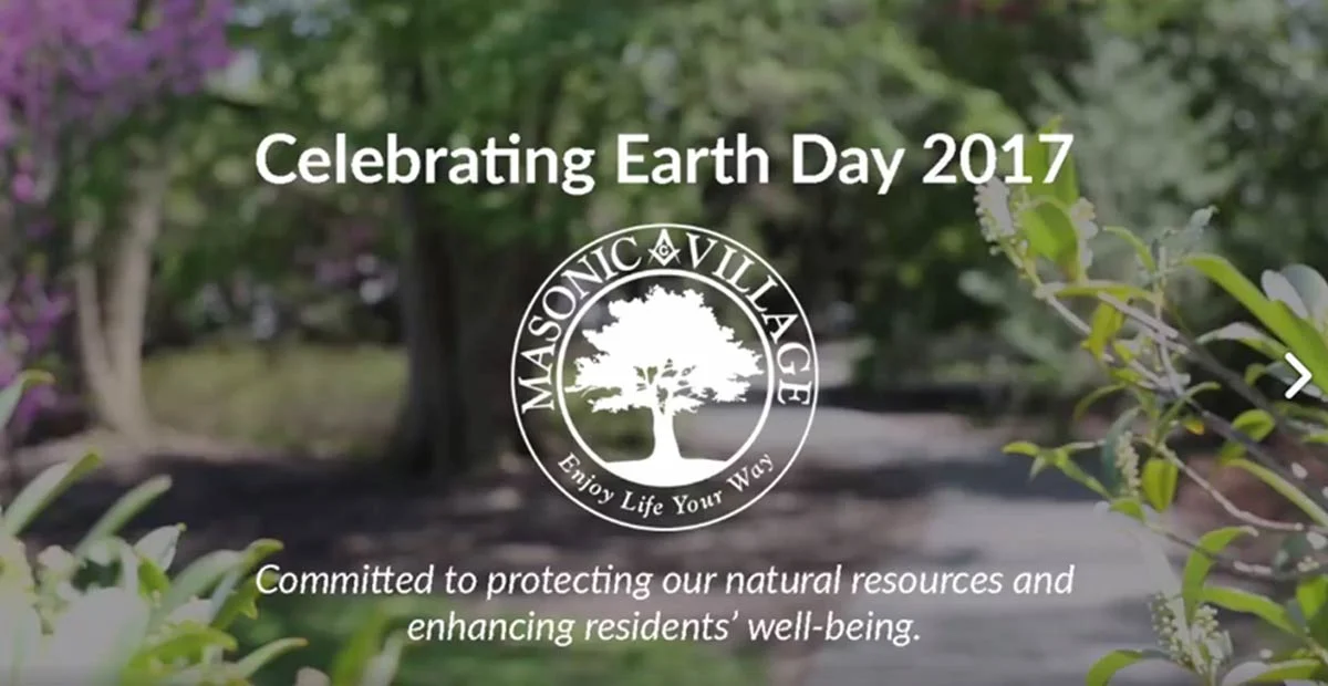 Out-of-focus trail with flowers and plants with text that reads, "Celebrating Earth Day 2017, Committed to protecting our natural resource and enhancing residents' well-being."