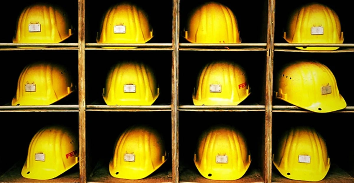 Yellow hard hats in wooden cubbies.