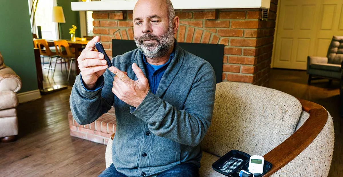 Man Testing Blood Glucose in his home.