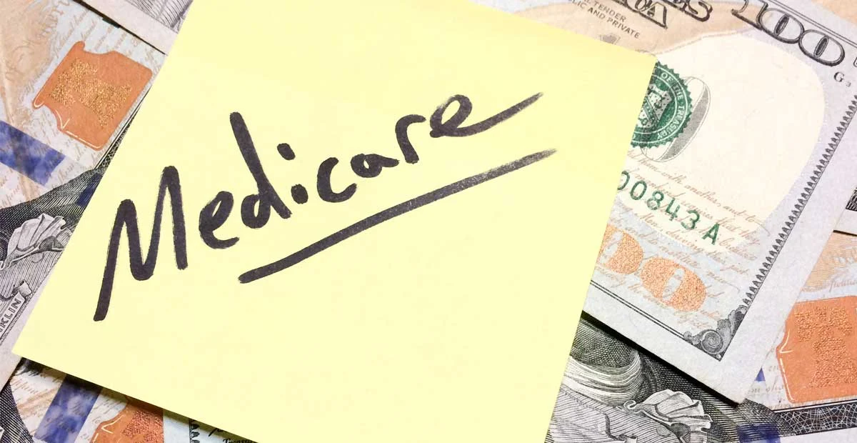 The word "Medicare" written on a sticky note laying on top of paper money.
