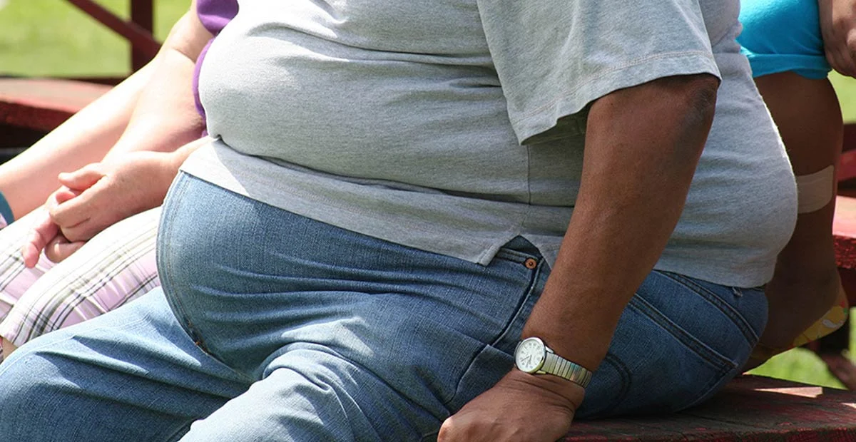 Closeup of person seated on a bench outdoors.