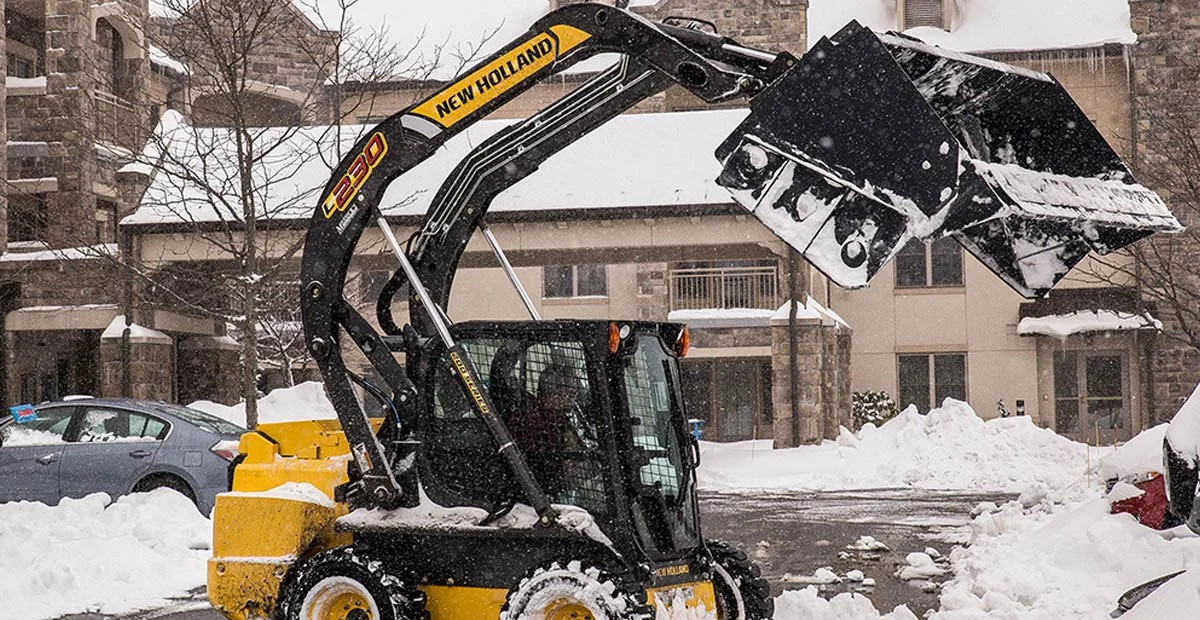 Snow plow working in parking lot during a snow storm.
