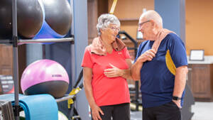 Happy couple standing together near exercise equipment in wellness center