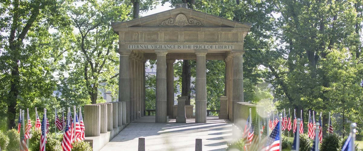 Hero_Veterans-Grove-06 Veterans grove with partial columns and American flags leading up to a loggia.