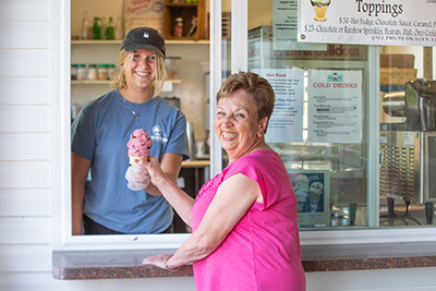 Server handing ice cream cone to resident