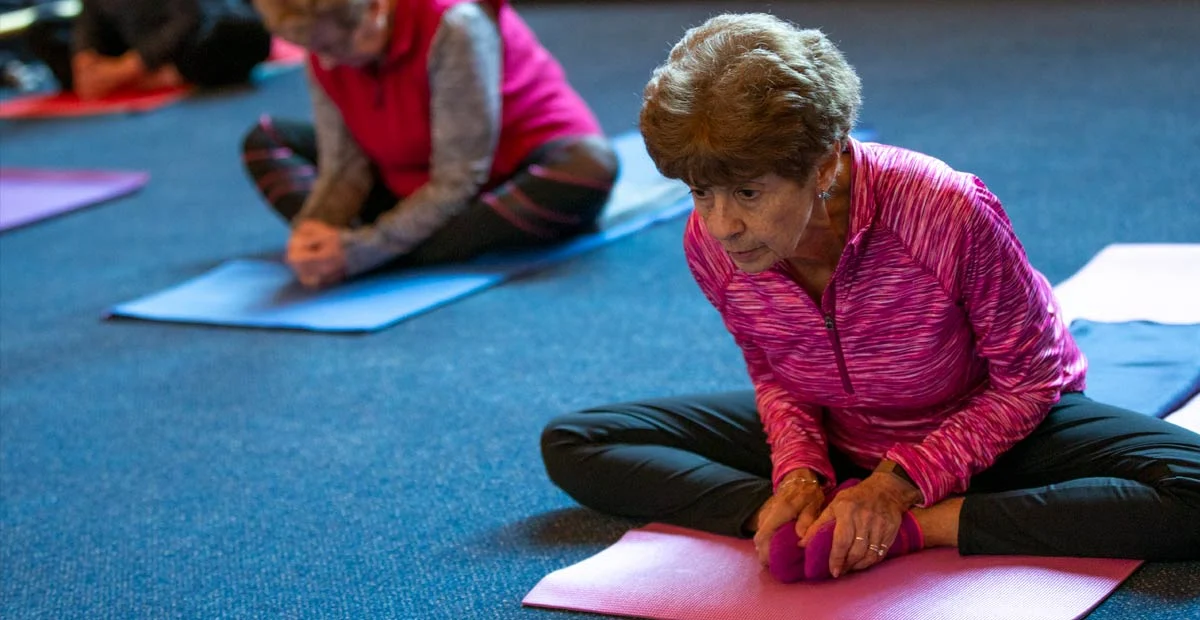 Woman leaning over while seated in yoga class.