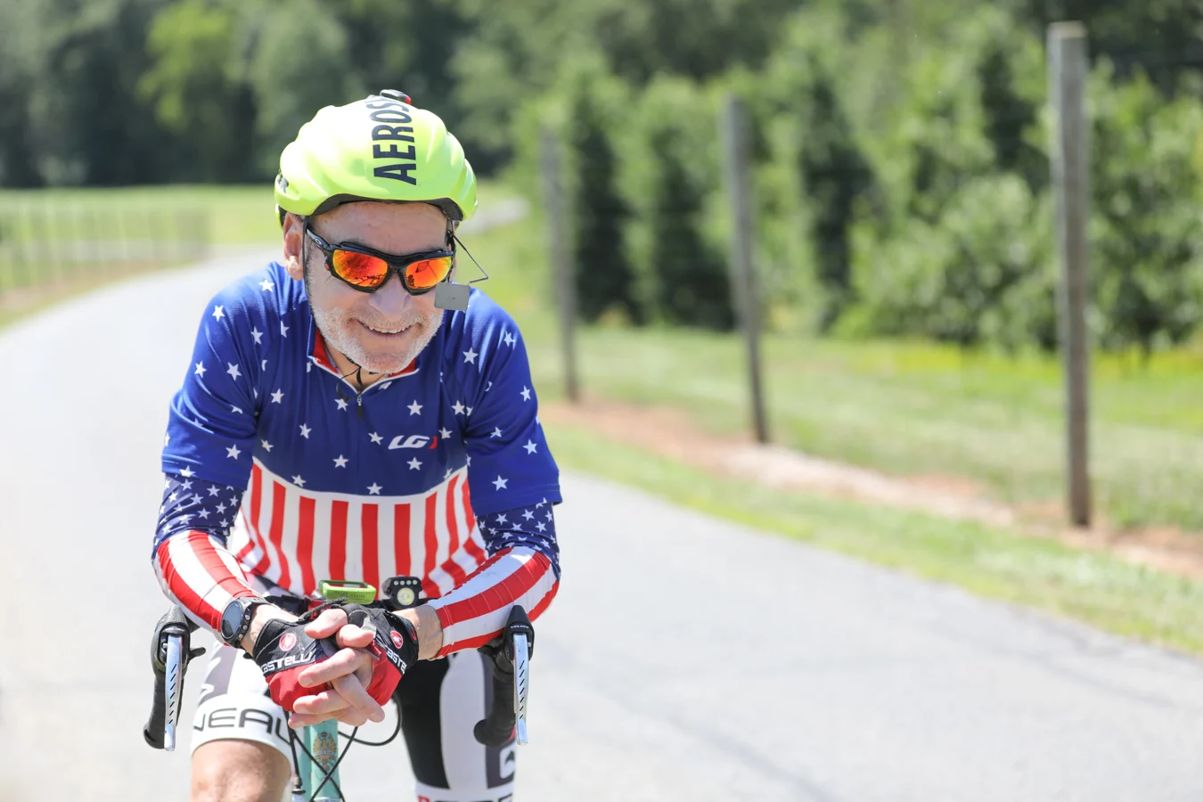 Smiling senior man wearing a helmet and biking outfit while riding his bicycle outdoors.