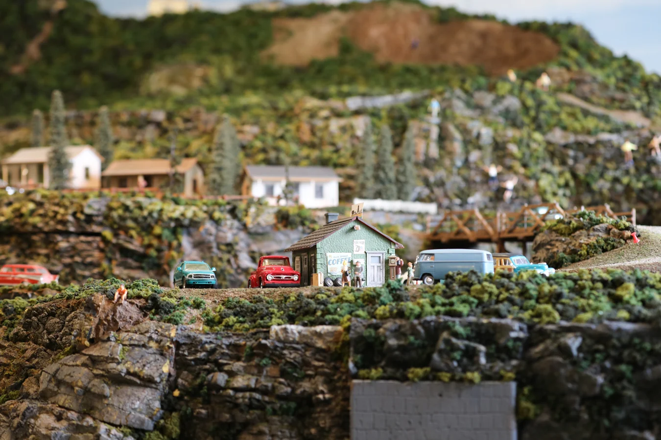 Closeup of cars around a small coffee shop in model train set.