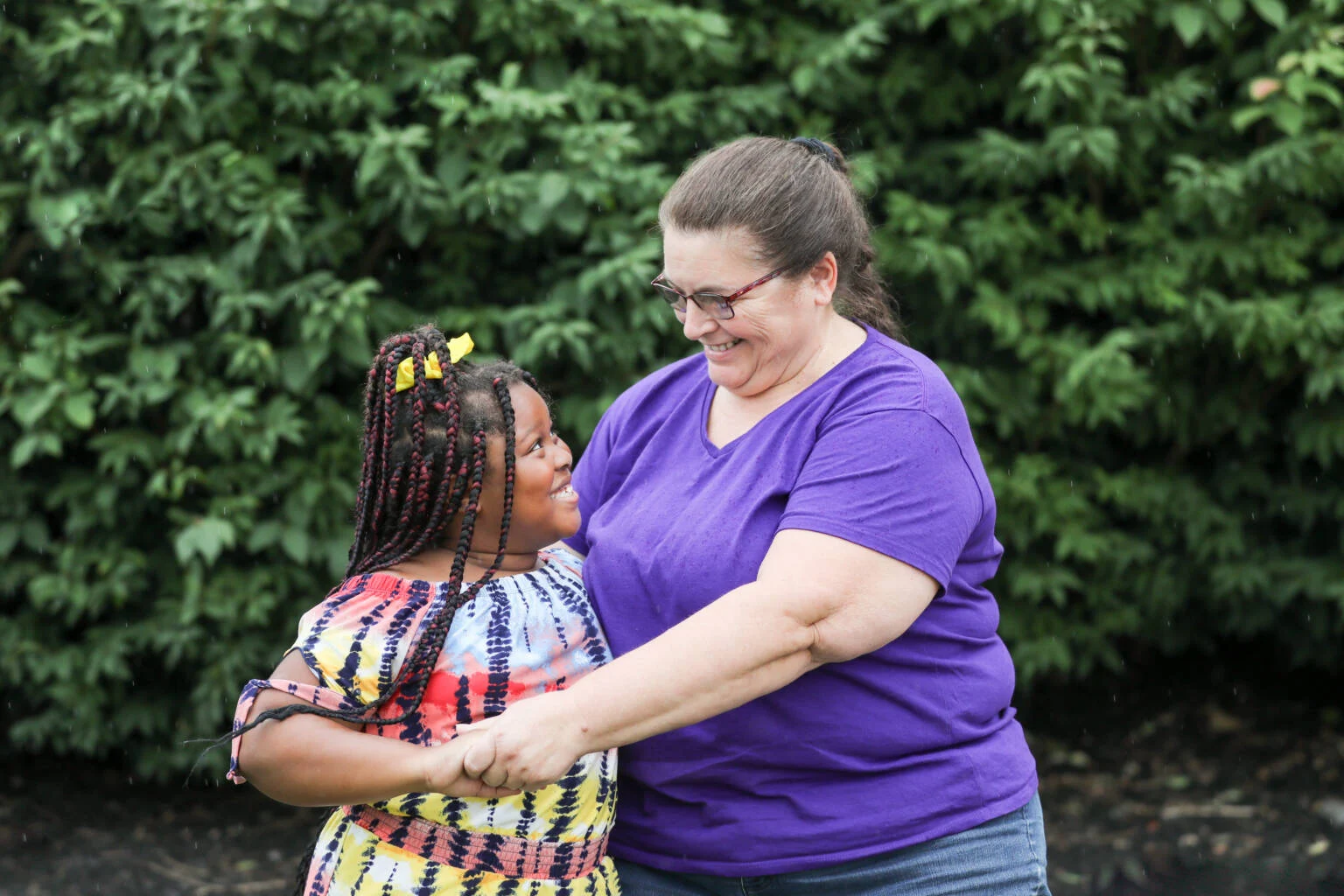 Children's home house parent embracing young girl, they are looking at each other and smiling.
