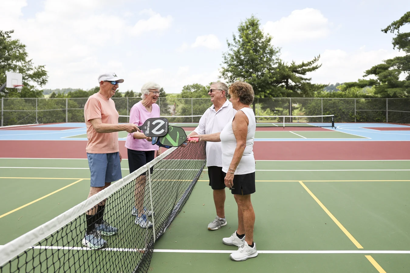 Group preparing to play pickleball while standing on a court.