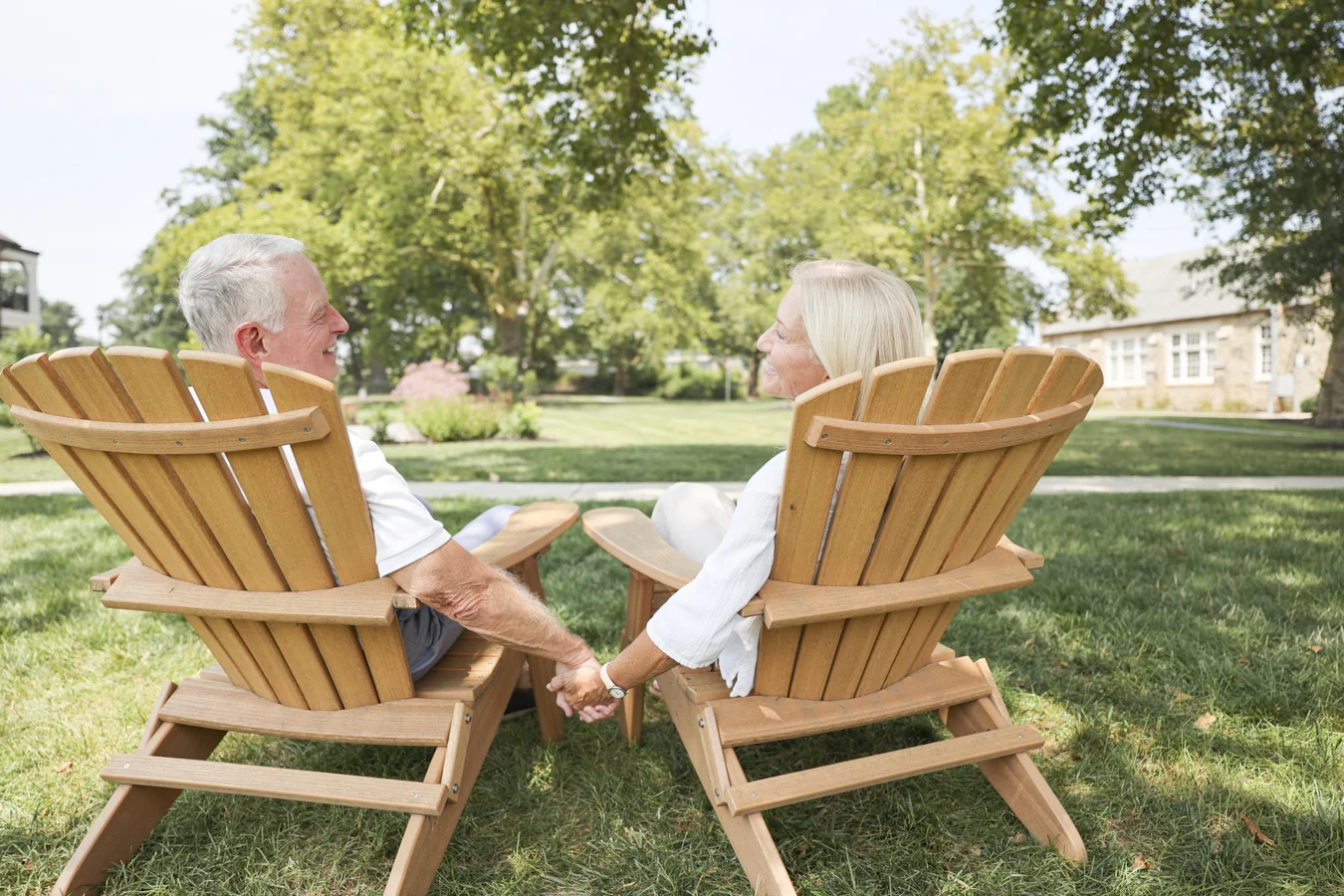 Senior couple holding hands in chairs.