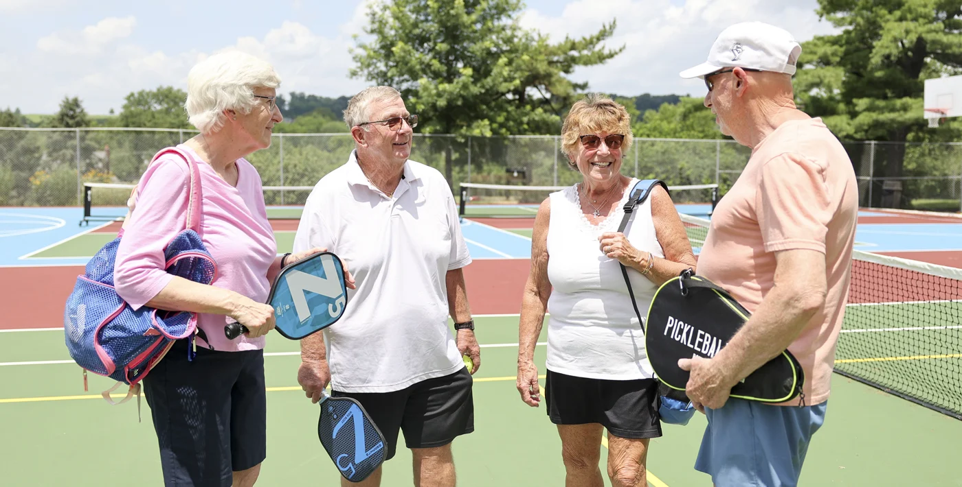 Residents holding pickleball equipment while standing on court.