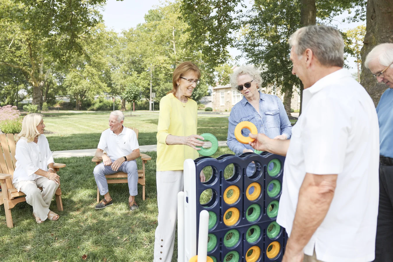 1W8A2242 Smiling group of seniors playing a large, outdoor boardgame.