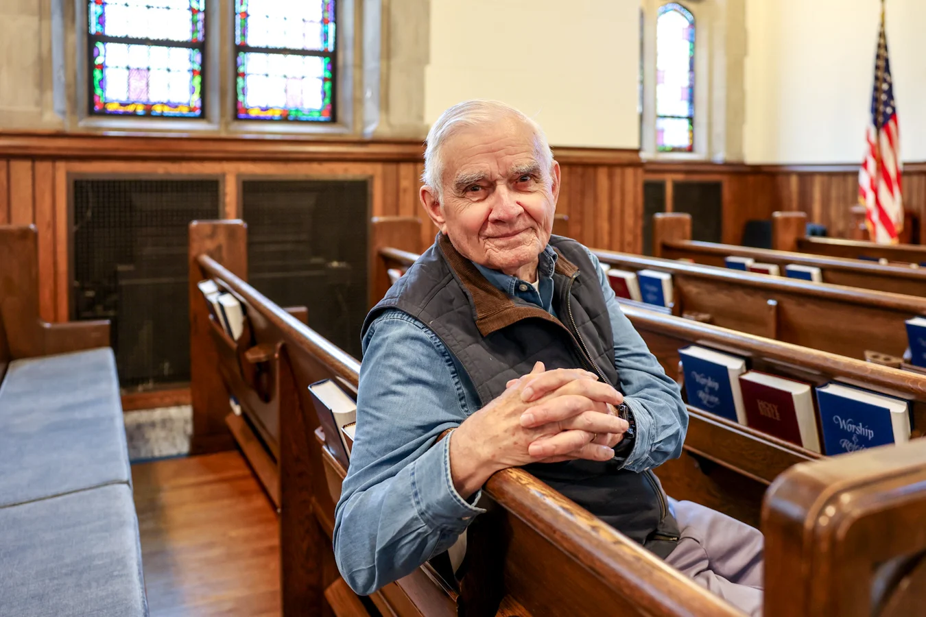 Smiling senior man seated in a church pew.