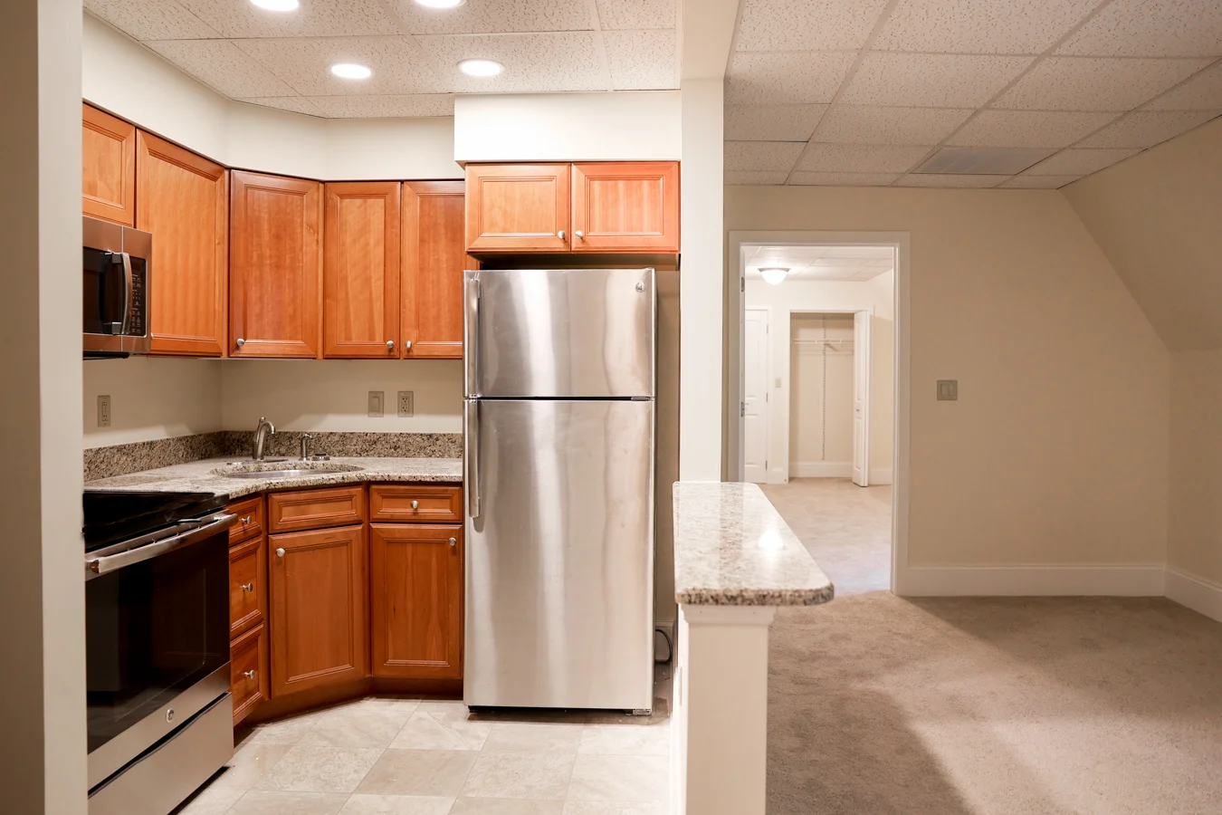1W8A7498 Well lit kitchen and living room with no furniture.