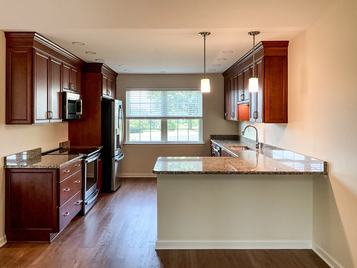 20240827_134127996_iOS Well-lit kitchen with wooden cabinets and stainless steel appliances.