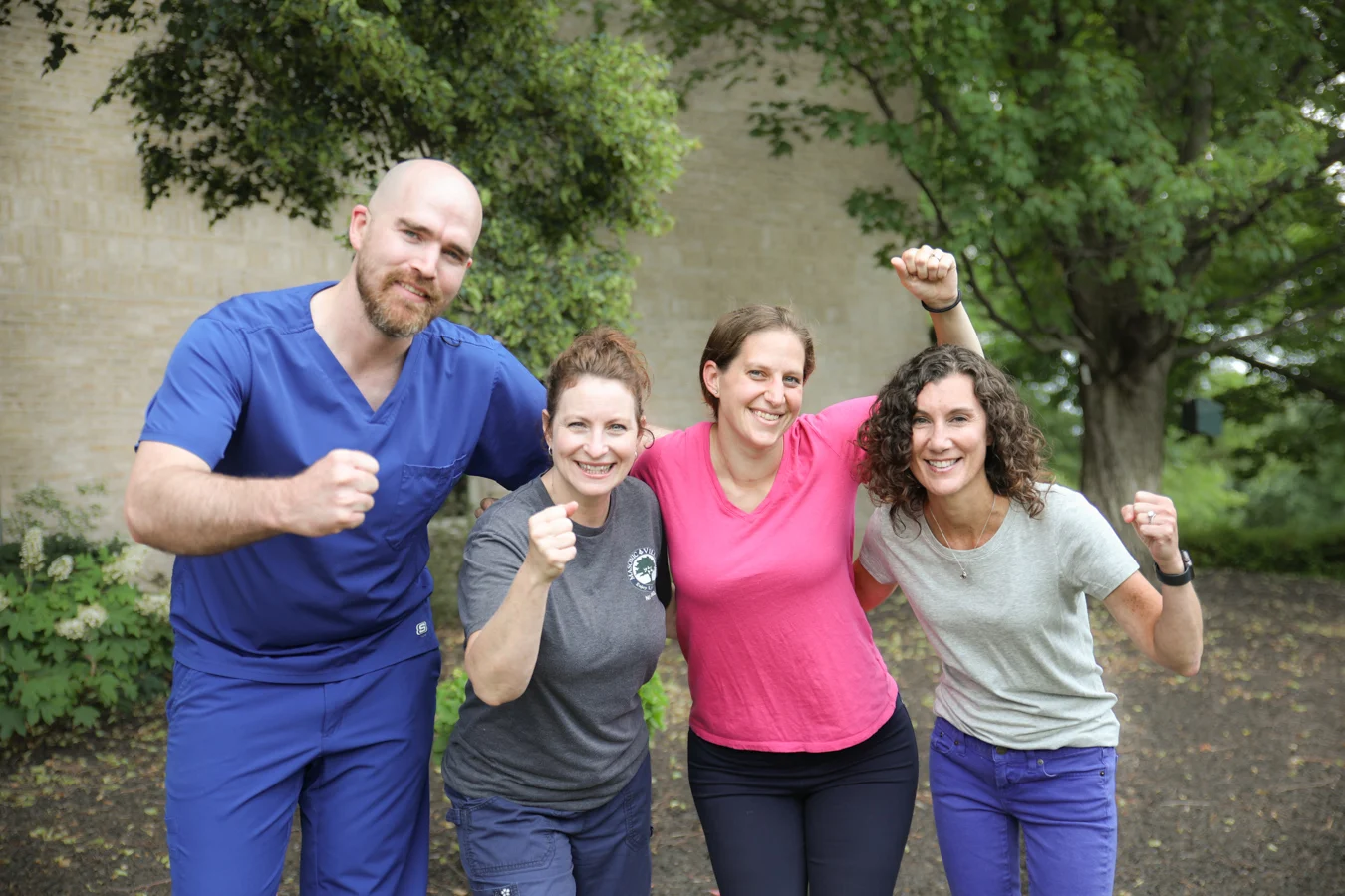 Smiling staff members celebrating together while posed outdoors.