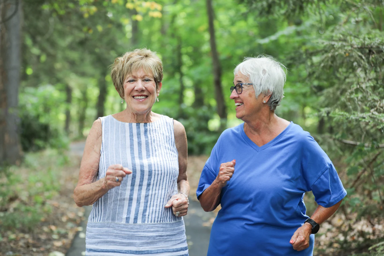 Smiling senior women jogging together outdoors.