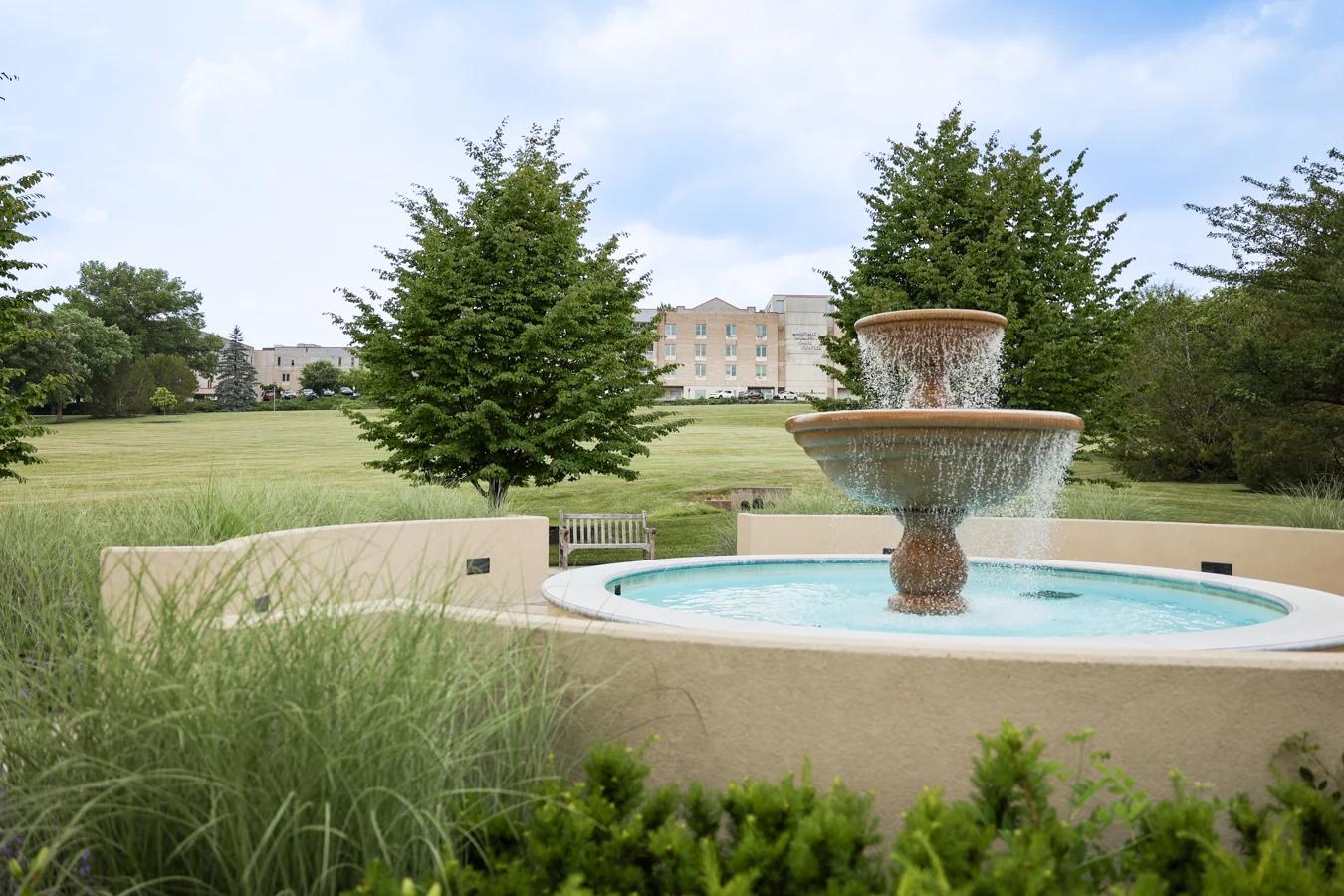 Picturesque outdoor fountain with sprawling stone building in the distance.