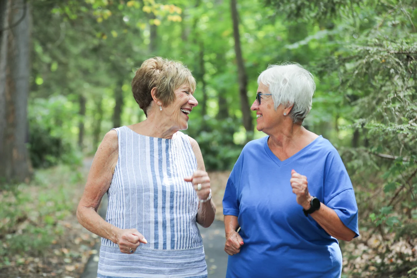 2V9A7763 Smiling senior women jogging together outdoors.